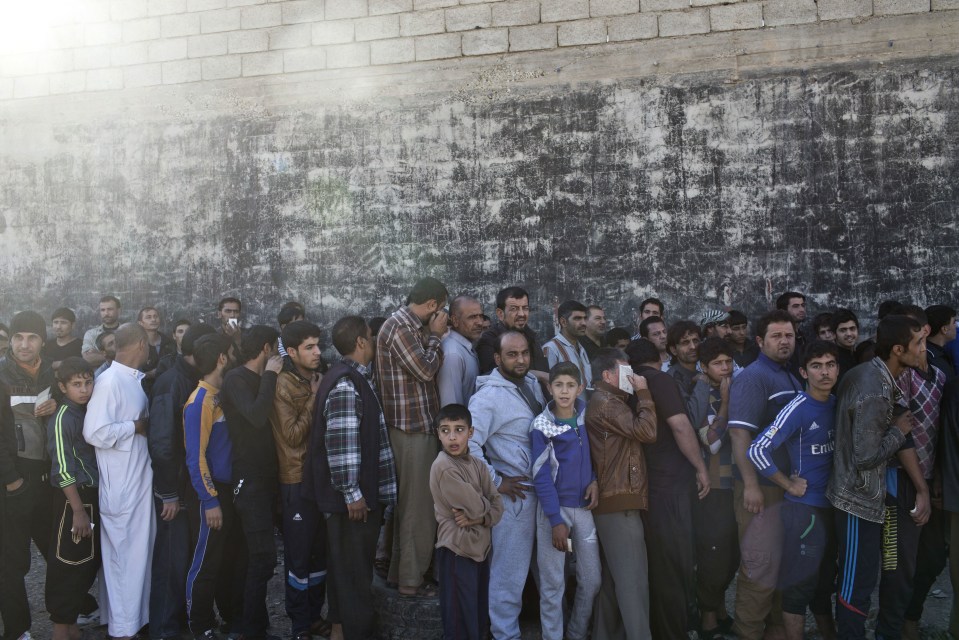 People queue up to get an aid packages in Gogjali after it is free by Iraqi troops