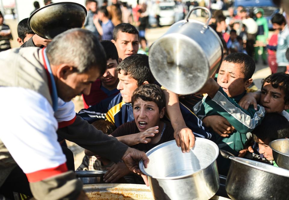 Displaced Iraqi boys wait to receive foo