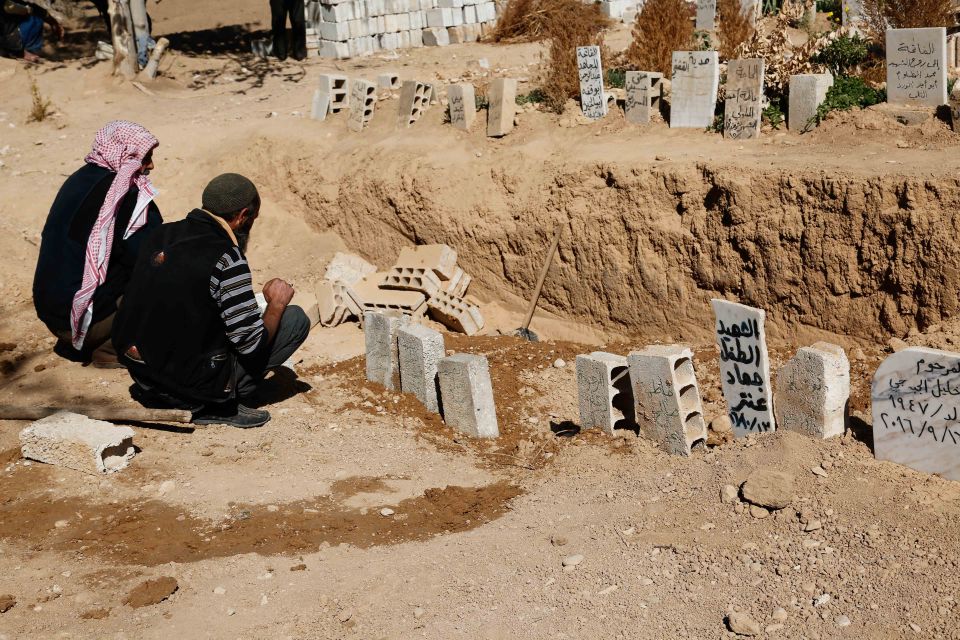 The father of one of the children killed in the shelling weeps over their grave