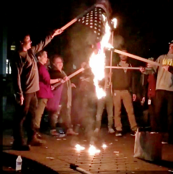 Clinton supporters were filmed setting fire to the US flag while marching through the streets of Portland