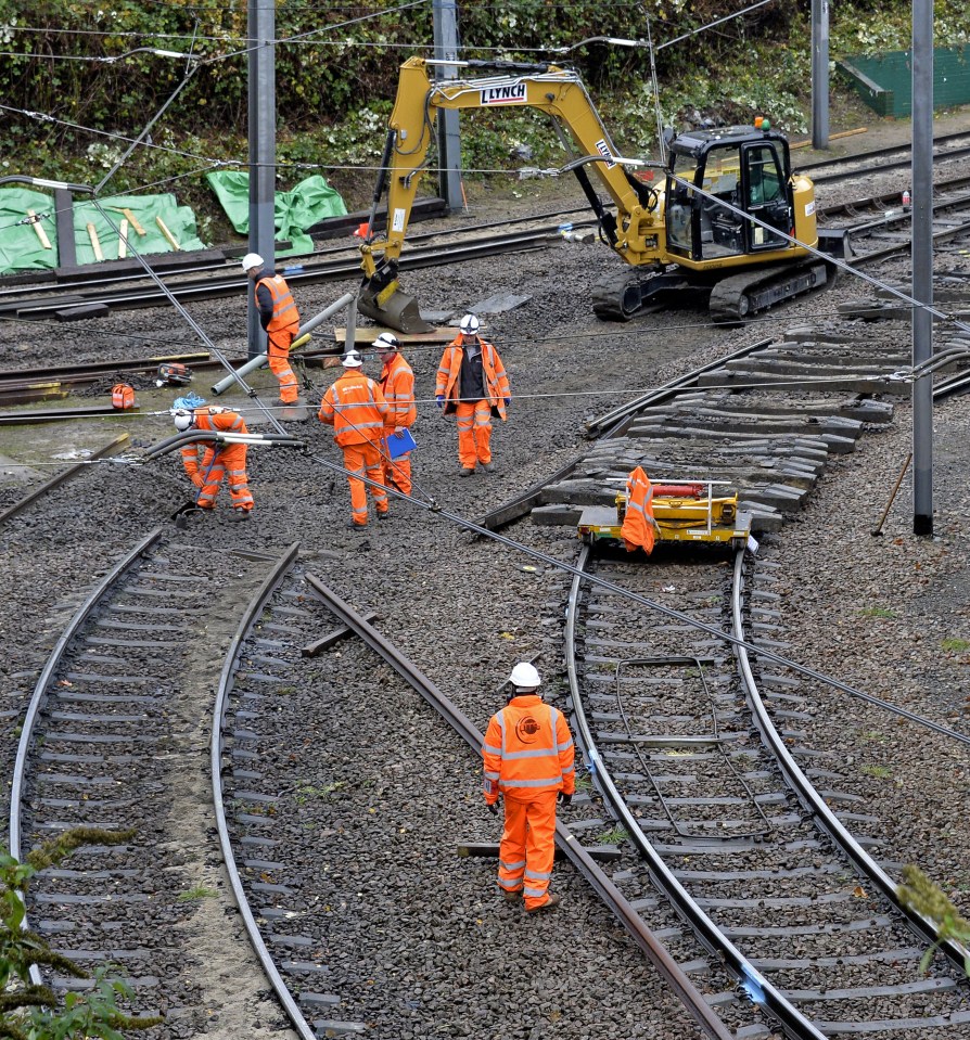 Rail workers at the site work to fix the track where the tram derailed on Wednesday which saw seven people killed