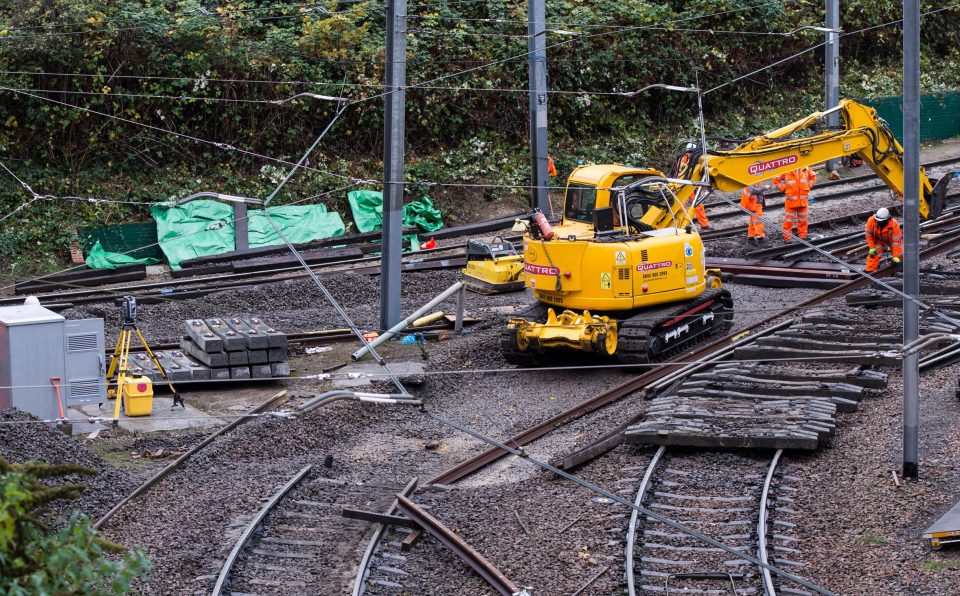 Rail workers at the site work to fix the track where the tram derailed on Wednesday which saw seven people killed 