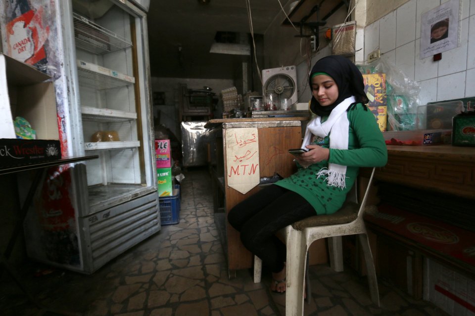 A schoolgirl uses her mobile phone inside a grocery shop with low supplies 