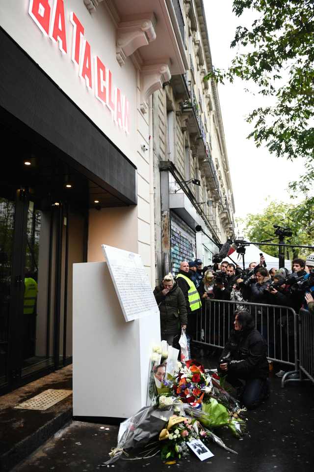 A woman pays her respect to victims in front of a commemorative plaque