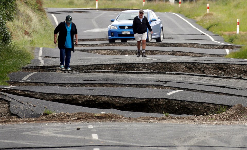 Local residents Chris and Viv Young look at damage caused by an earthquake, along State Highway One near the town of Ward