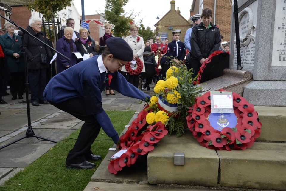 A child lays a wreath at the memorial service which hundreds of people attended