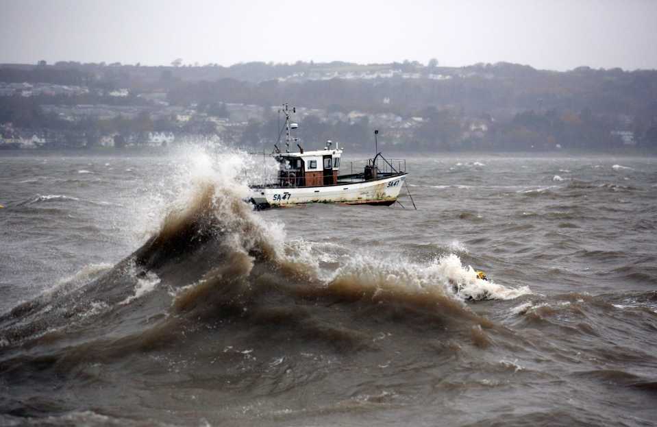 A boat bobs about in the waves in Mumbles promenade in Swansea, Wales
