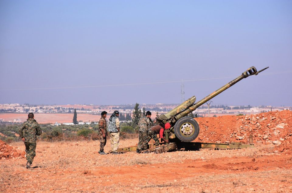 Syrian pro-government fighters fire a Russian 122mm howitzer gun