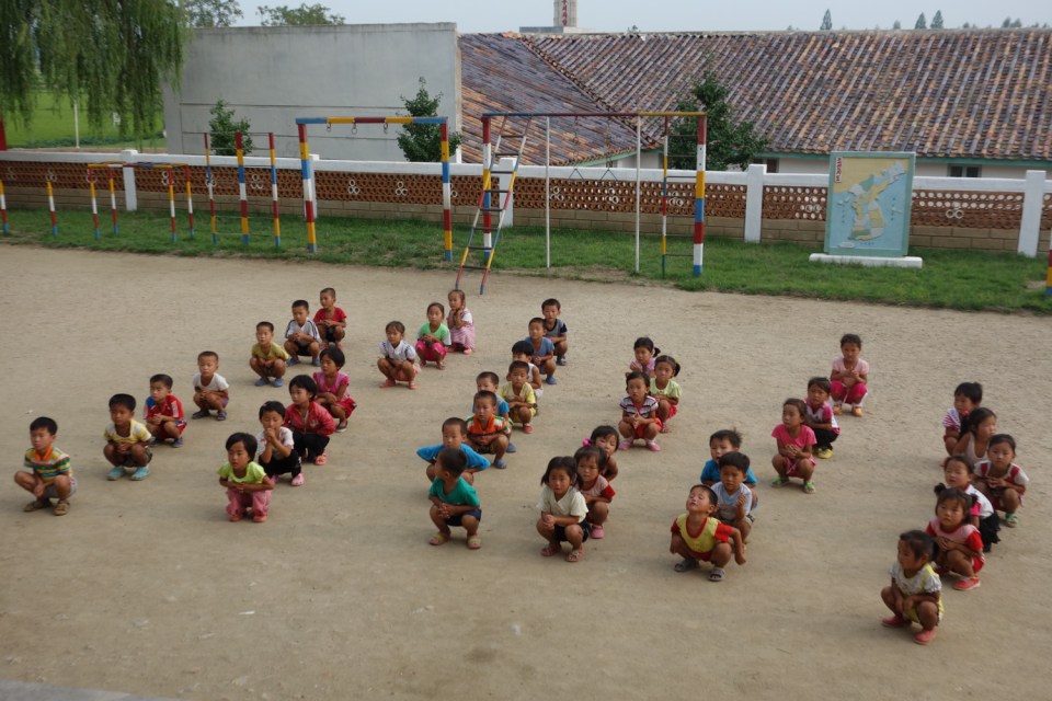 Children await further instructions in the schoolyard of a co-operative farm in South Hamgyang province