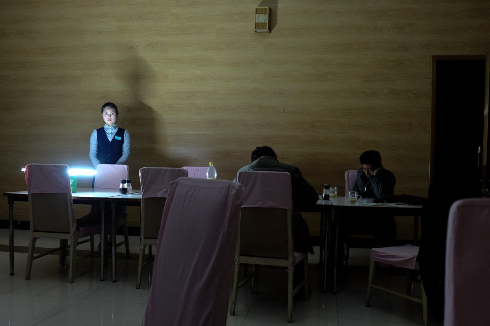A waitress places a battery-powered light on a table during a blackout in Chongjin