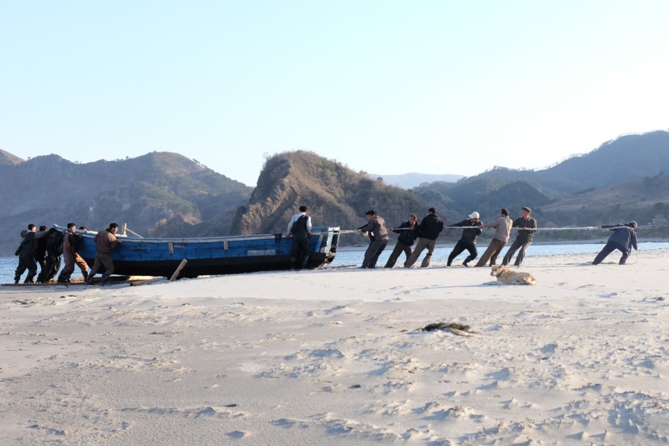 Villagers haul a boat over wooden rollers in outer Chilbo