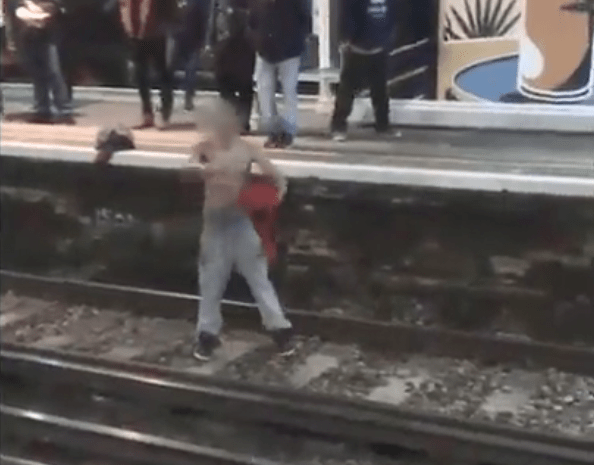 A man has been caught on camera taking off his shirt and launching into a rap on the train tracks on Monday night