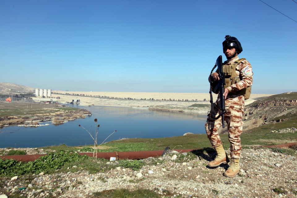 An Iraqi Kurdish Peshmerga stands guard near the Mosul Dam amid fears ISIS may try to make it burst