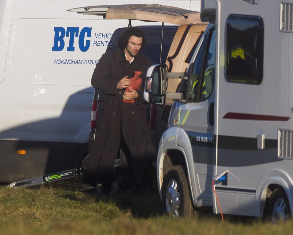 Aiden Turner clutches a hot water bottle on a bitterly cold set of Poldark near Cirencester