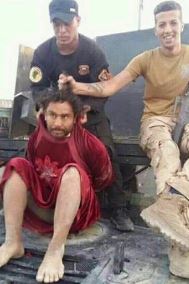 A very unhappy-looking ISIS militant is mocked by his captors