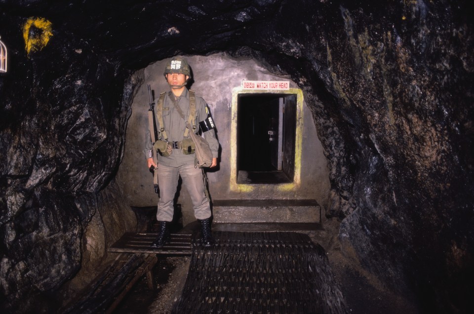 A soldier is seen standing guard outside the entrance of this tunnel 