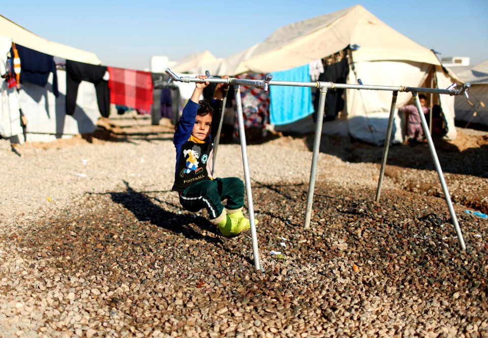 A little boy plays on a makeshift climbing frame after being forced to flee Mosul 