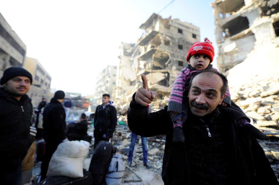 People, who evacuated the eastern districts of Aleppo, stand with their belongings in a government held area of Aleppo