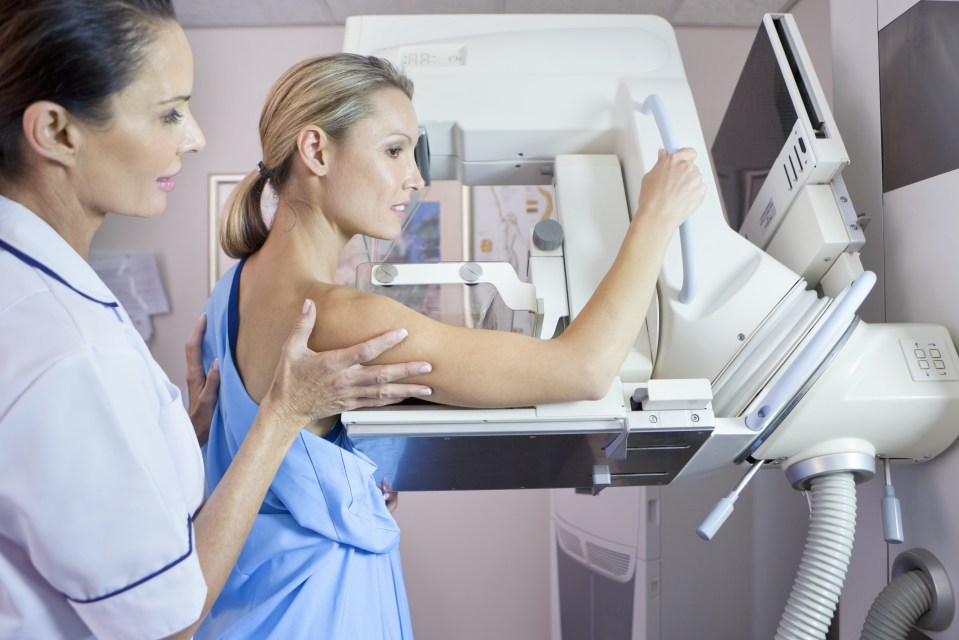 Nurse preparing patient for mammogram at x-ray machine in hospital