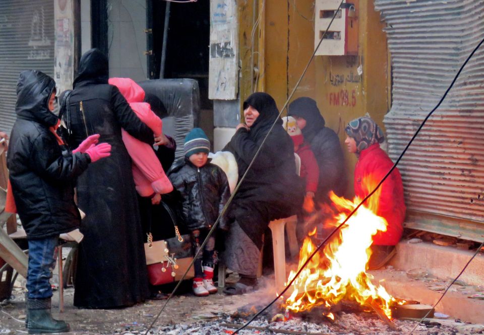 Civilians try to stay warm by a fire after fleeing from the fighting 