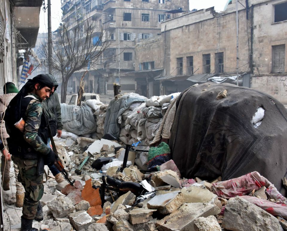 Syrian government fighters walk in Aleppo's newly captured Al-Kalasseh neighbourhood