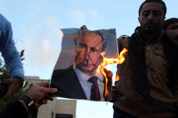 Protesters burn a photo of Russian President Vladimir Putin during a protest in front of Russian embassy in Amman, Jordan