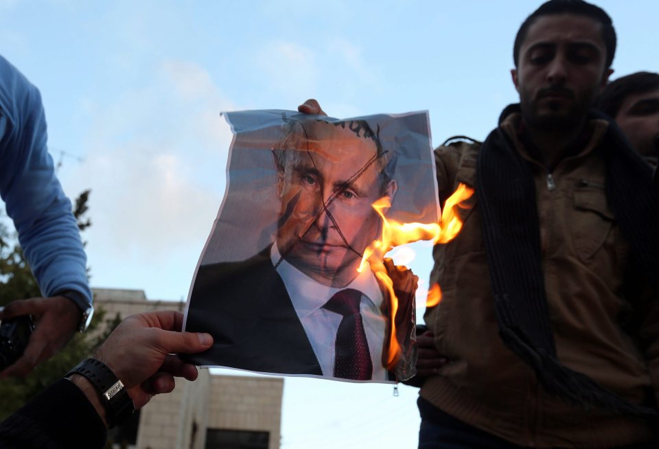 Protesters burn a photo of Russian President Vladimir Putin during a protest in front of Russian embassy in Amman, Jordan