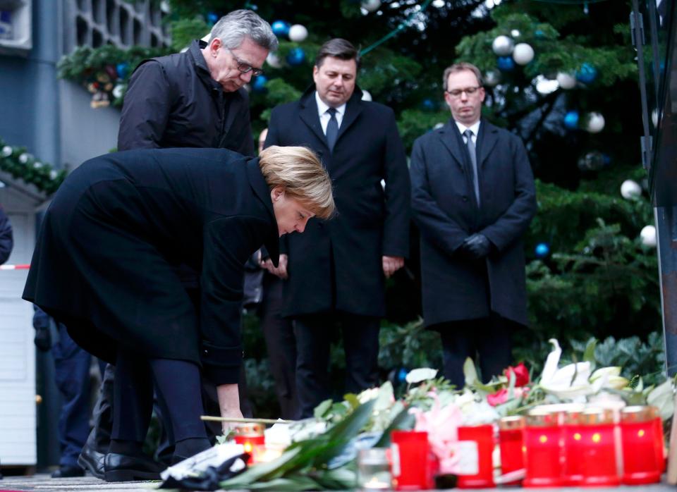 The German premier adds to wreaths left at the scene during a sombre ceremony