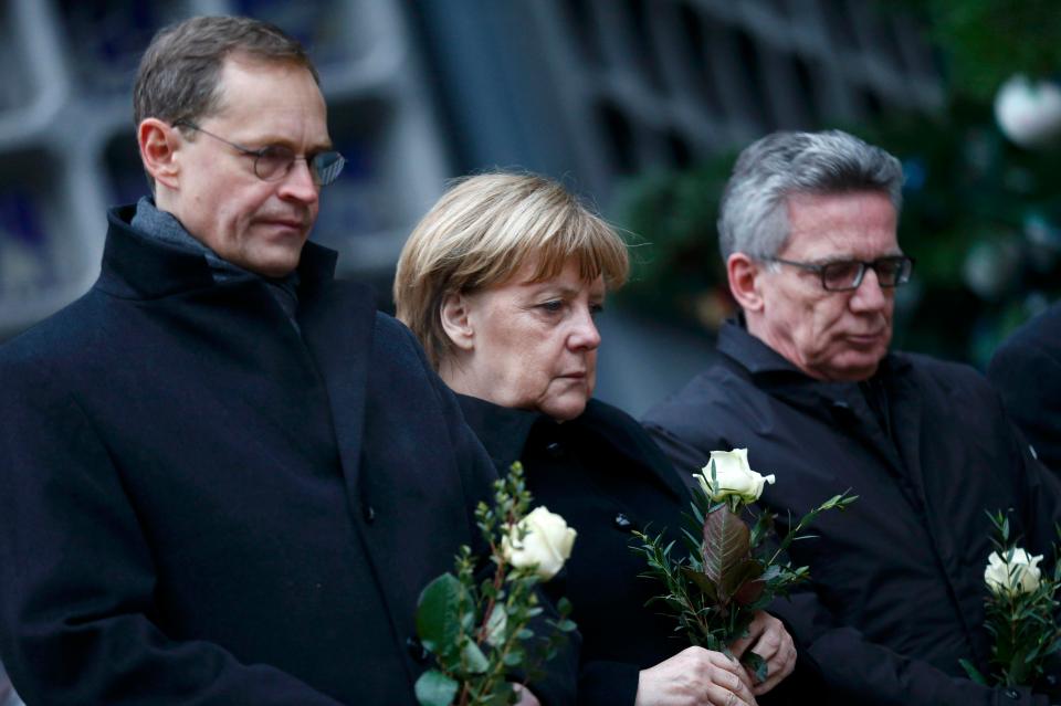  Merkel, Berlin mayor Michael Mueller, left, and German interior minister Thomas de Maiziere, right, laid flowers at the scene