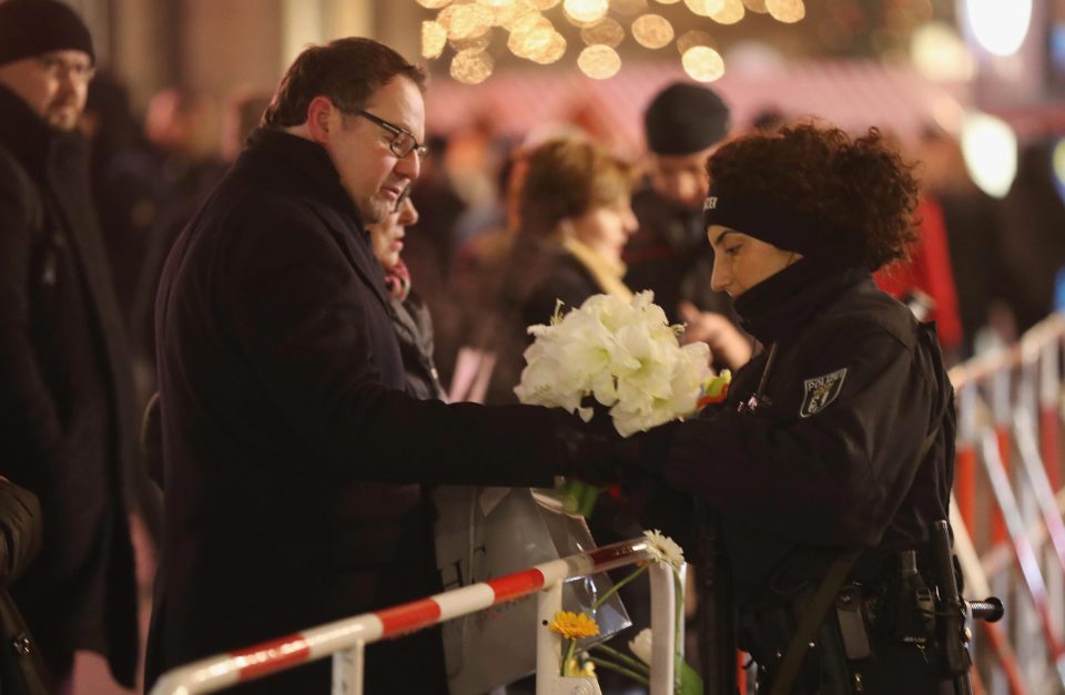 A man passes flowers to a police officer to place at the vigil