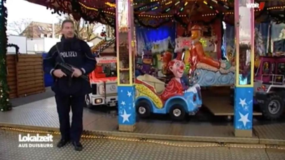 Footage of a machine gun-wielding cop standing guard outside a merry-go-round at a Christmas market has sparked a heated debate on social media