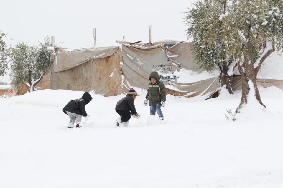 Youngsters make snowballs as a thick blanket of snow covers the ground in the Syrian city of Azaz