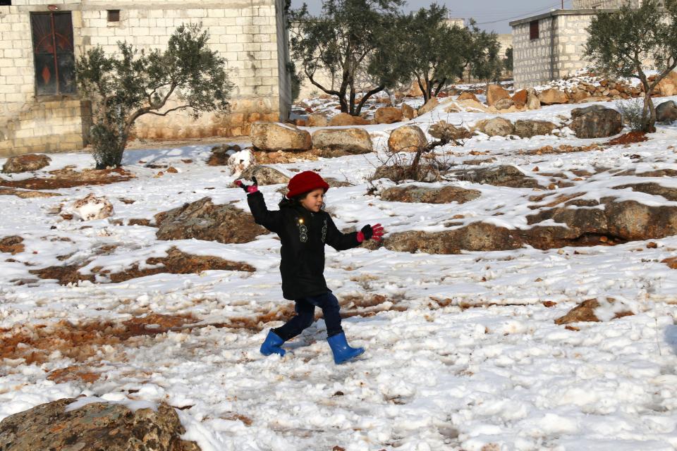 A child plays in the snow after her family arrived in the town from a rebel-held pocket of Syria's northen city of Aleppo