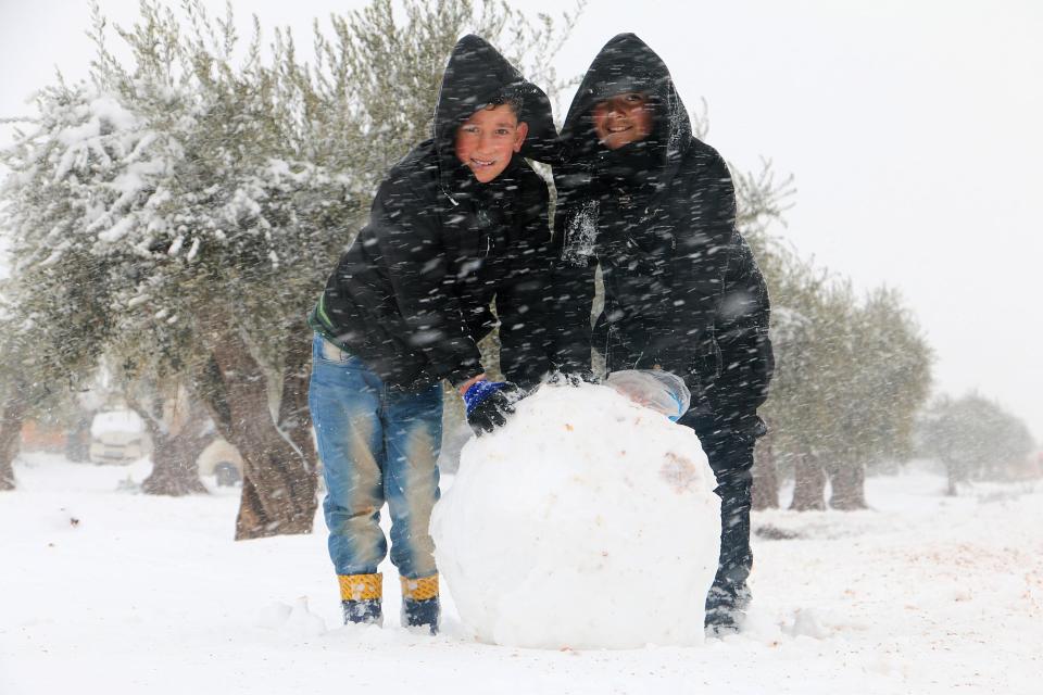Kids in Azaz making in snowman as snow falls in the tent city 