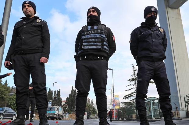 Authorities stand guard with red carnations left near the nightclub targeted in the terrorist attack