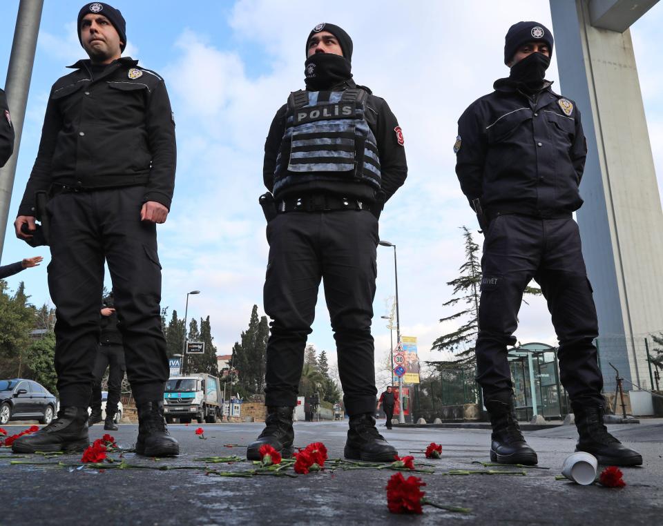 Authorities stand guard with red carnations left near the nightclub targeted in the terrorist attack