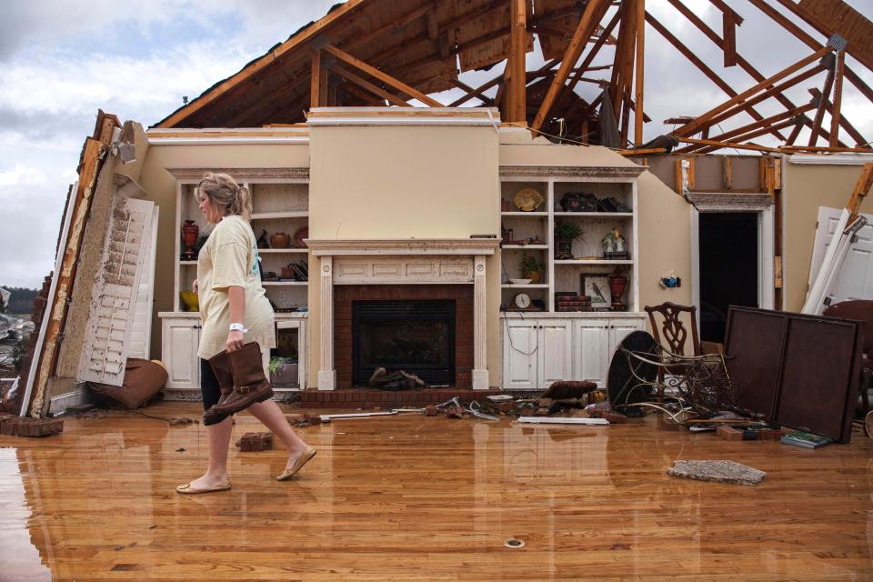  Jenny Bullard carries a pair of boots from her home that was damaged by a tornado