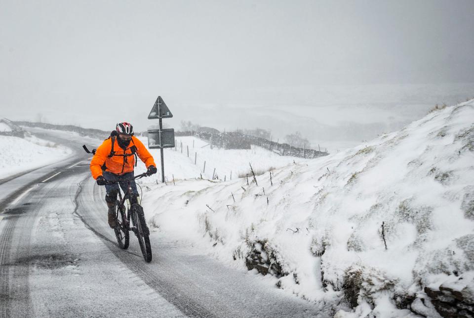  A cyclist on the Buttertubs Pass in the Yorkshire Dales as snow hit the UK at the weekend