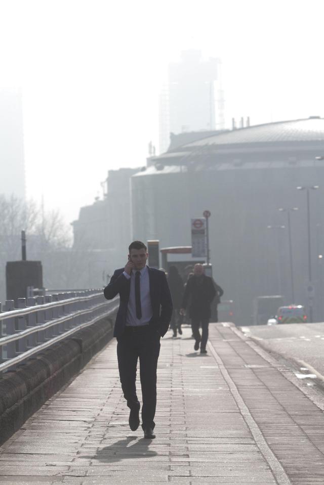  A commuter walks to work in London as the sun tried to break through the clouds this morning