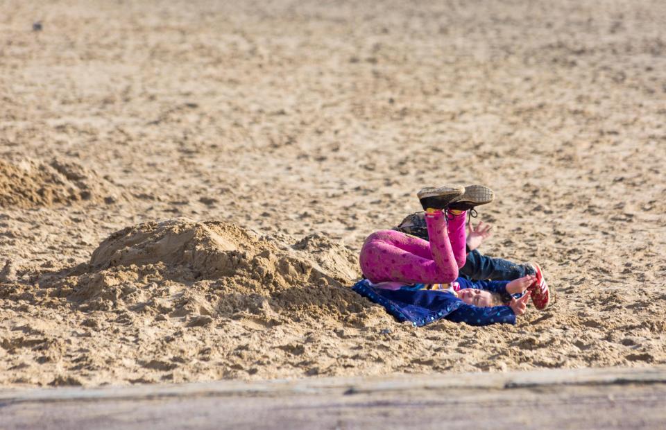 A youngster larks about under the sun on a beach in Bournemouth today 