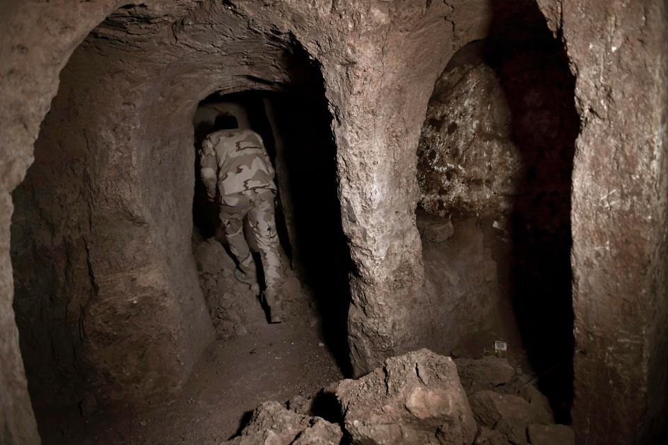 An Iraqi soldier leads reporters into the ancient underground palace 