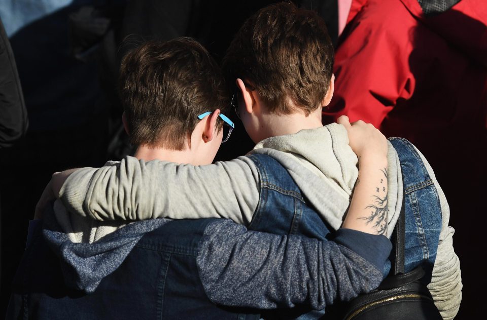 Two well-wishers comfort each other as the city roars its defiance