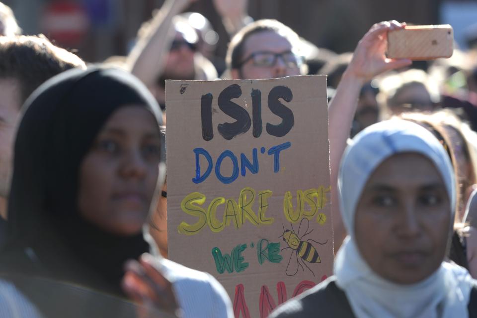A man holds a sign saying: 'ISIS don't scare us, we're Mancs'