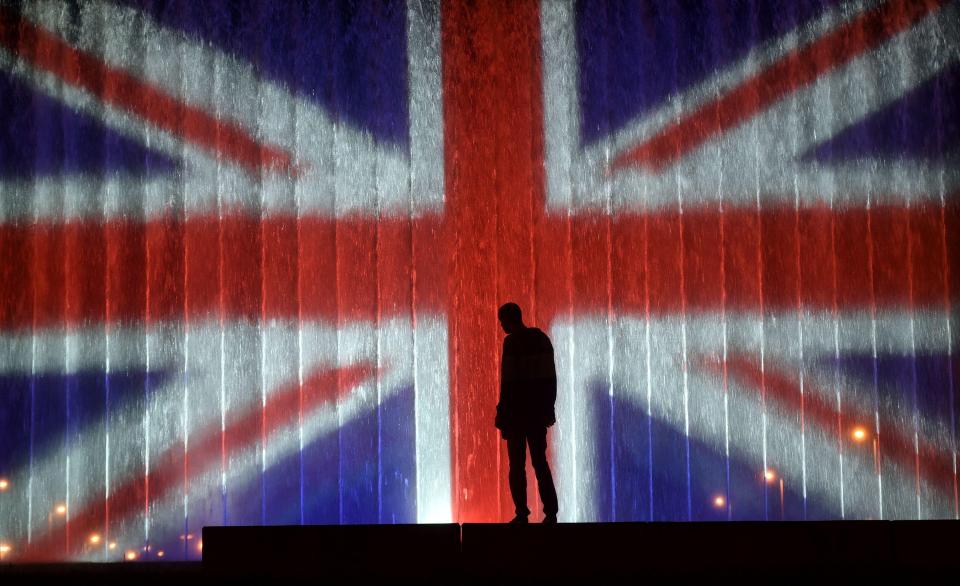 A man stands in front of a fountain illuminated with the colours of the UK flag in Zagreb, Croatia