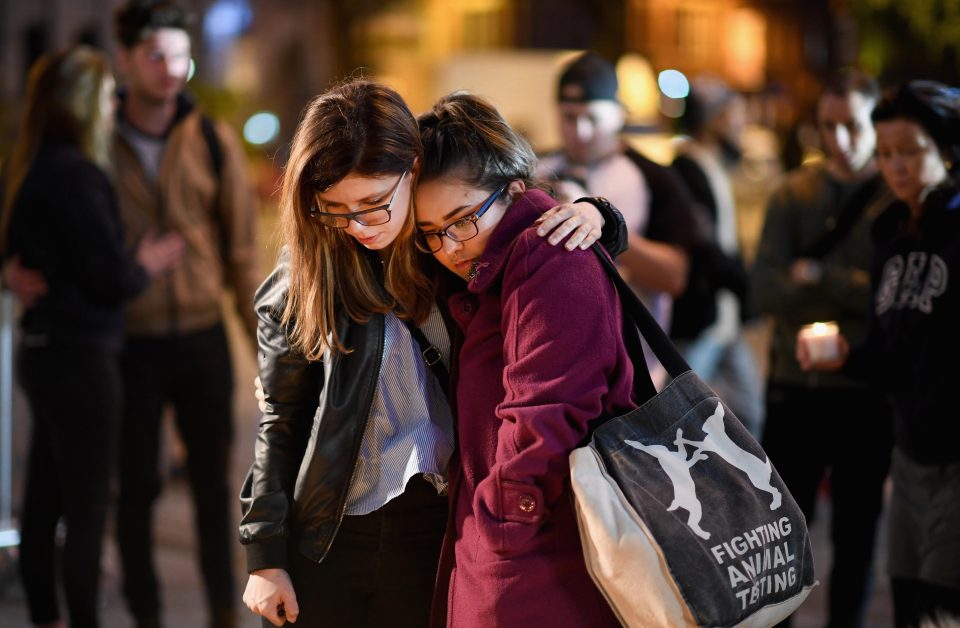  Two women console each other at a candle-lit vigil