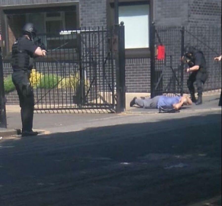  A man lies on the ground as police point guns at him during a large-scale response to a suspicious package