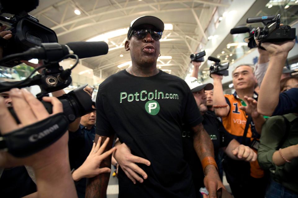  The basketball player is surrounded by reporters at Beijing's international airport before boarding a plane to North Korea
