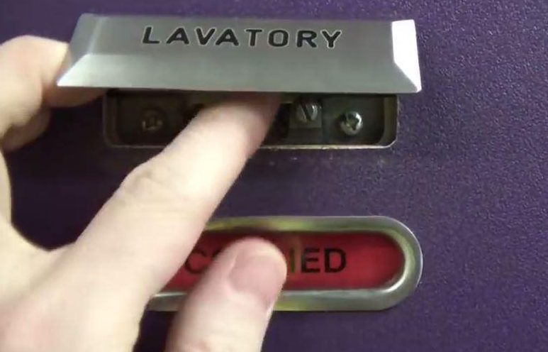 Underneath the lavatory sign will be a catch that, once turned, will turn the lock