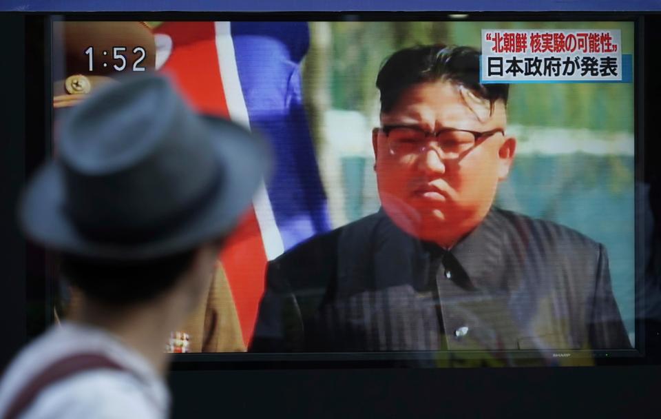A man walks past a TV news on screen reporting North Korea's a possible nuclear test