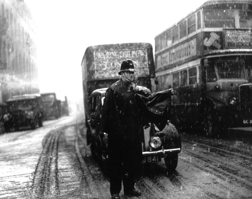 A policeman on point duty at Charing Cross in London braves some seasonable wintry weather